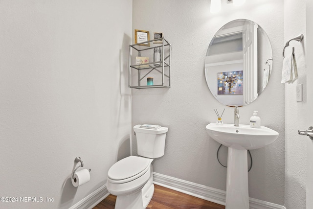 half bath featuring toilet, wood finished floors, and baseboards