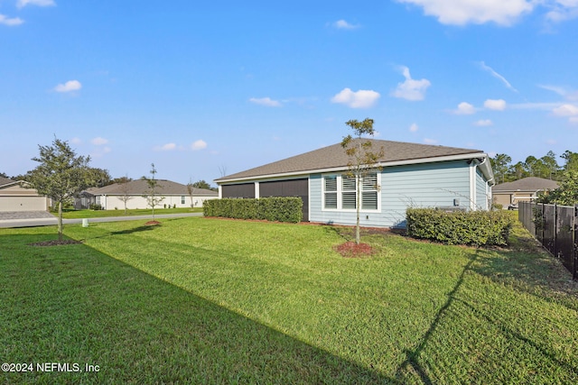 rear view of property featuring a lawn and fence