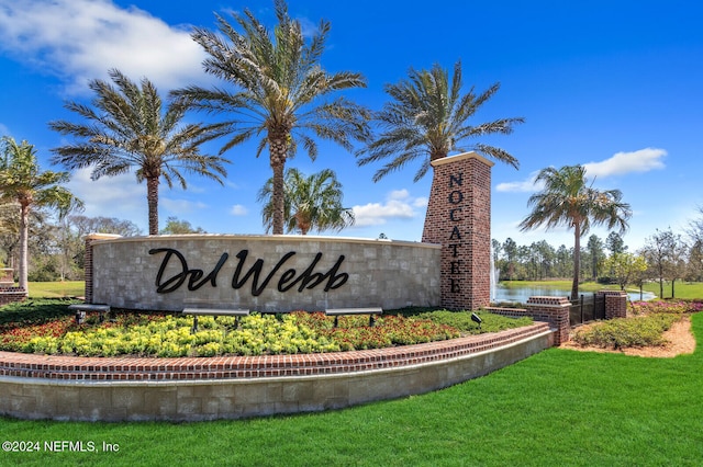 community / neighborhood sign featuring a lawn and a water view