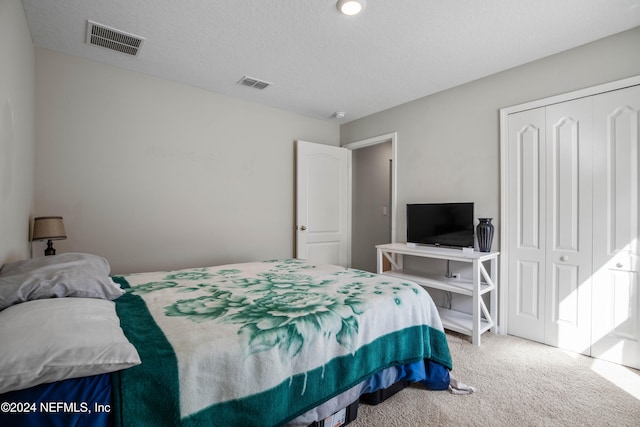 bedroom with a closet, carpet, and a textured ceiling