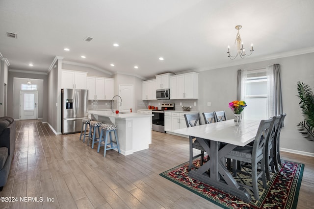 dining room with light hardwood / wood-style flooring, ornamental molding, a chandelier, and lofted ceiling