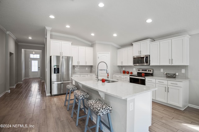 kitchen featuring light hardwood / wood-style flooring, an island with sink, stainless steel appliances, crown molding, and sink