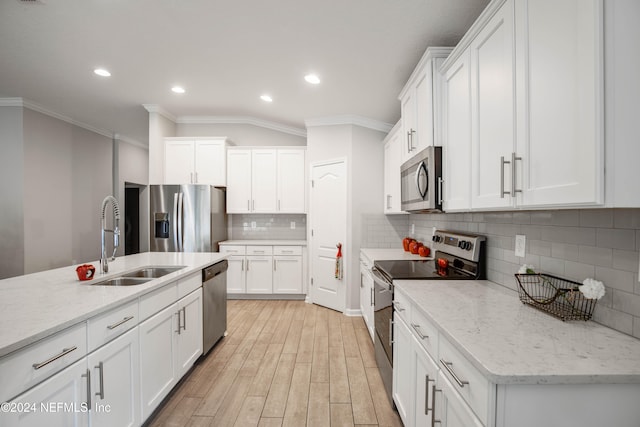 kitchen with appliances with stainless steel finishes, sink, light hardwood / wood-style floors, white cabinets, and decorative backsplash