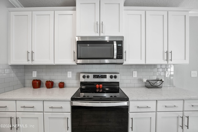 kitchen with white cabinetry, stainless steel appliances, and light stone countertops