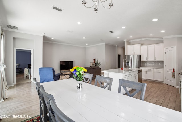 dining area featuring light hardwood / wood-style floors, ornamental molding, sink, and vaulted ceiling