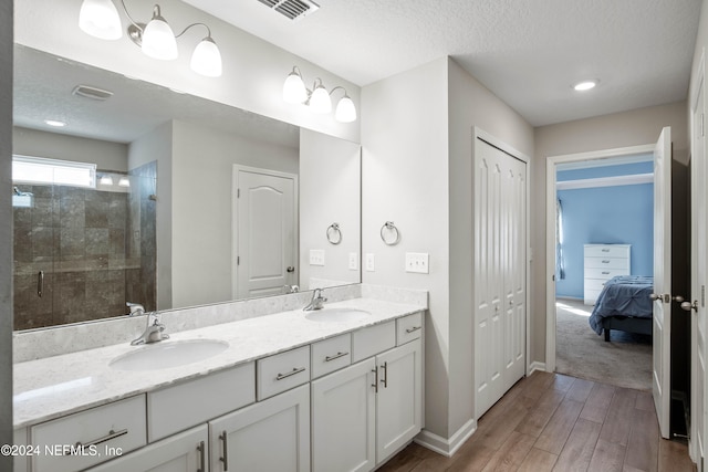 bathroom featuring vanity, hardwood / wood-style floors, a shower with shower door, and a textured ceiling