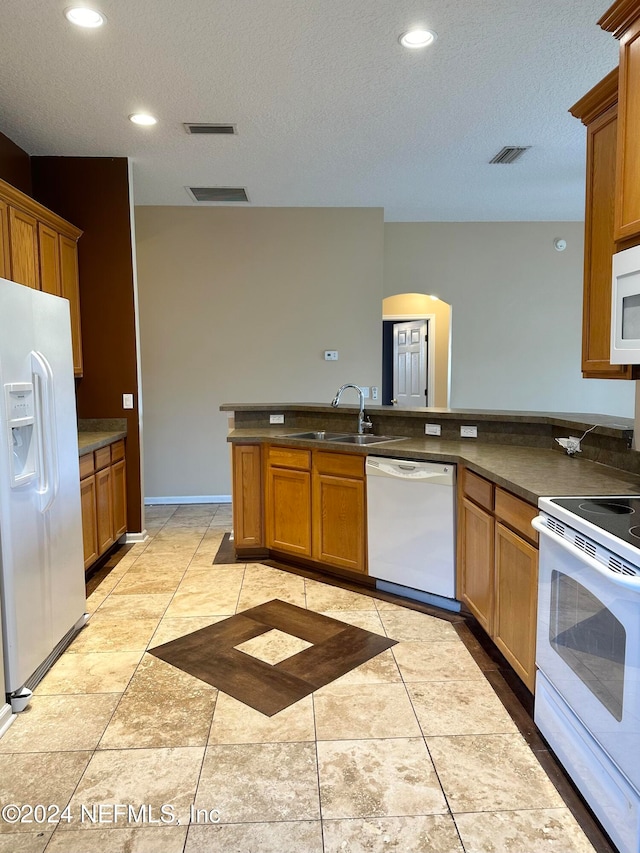 kitchen with white appliances, sink, a textured ceiling, kitchen peninsula, and light tile patterned floors