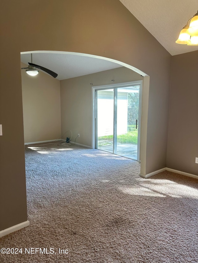 unfurnished room featuring lofted ceiling, a textured ceiling, carpet flooring, and ceiling fan