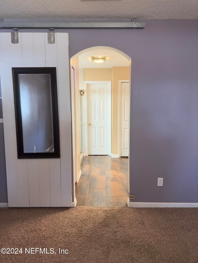 hallway featuring a textured ceiling and carpet floors