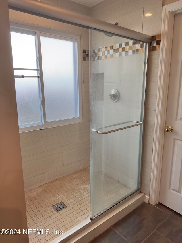 bathroom featuring an enclosed shower, tile walls, and tile patterned flooring