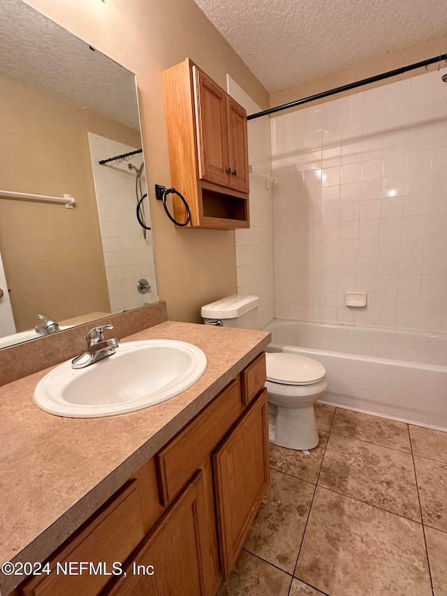 full bathroom featuring a textured ceiling, toilet, tile patterned floors, tiled shower / bath, and vanity