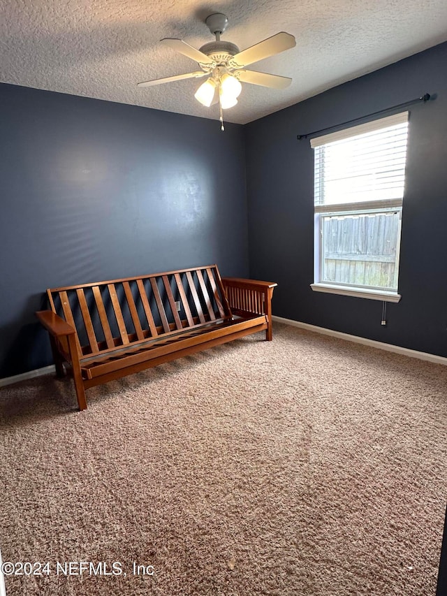 unfurnished bedroom featuring carpet, ceiling fan, and a textured ceiling