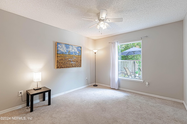 spare room featuring a textured ceiling, light colored carpet, and ceiling fan