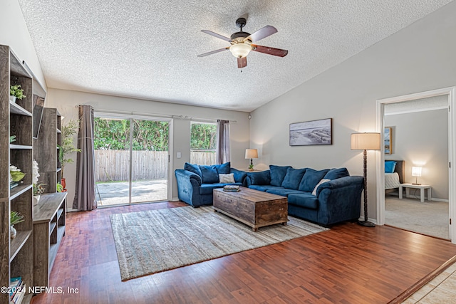 living room featuring light hardwood / wood-style flooring, a textured ceiling, vaulted ceiling, and ceiling fan