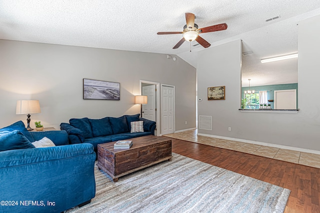 living room featuring a textured ceiling, wood-type flooring, ceiling fan with notable chandelier, and vaulted ceiling