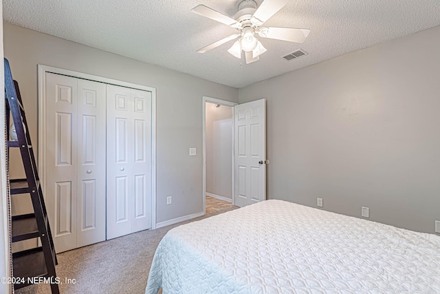 carpeted bedroom with a closet, a textured ceiling, and ceiling fan