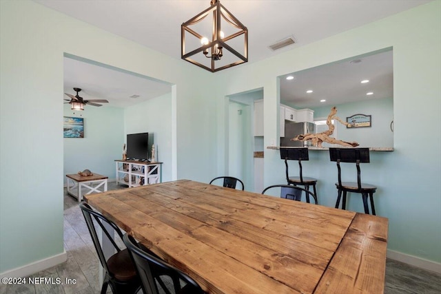 dining room with dark hardwood / wood-style floors and ceiling fan with notable chandelier