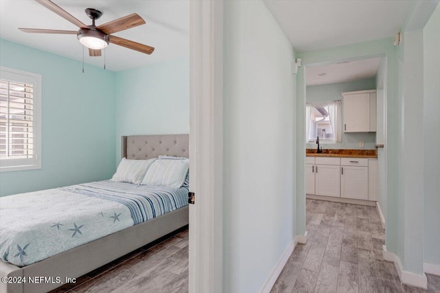 bedroom with connected bathroom, sink, light hardwood / wood-style floors, and ceiling fan