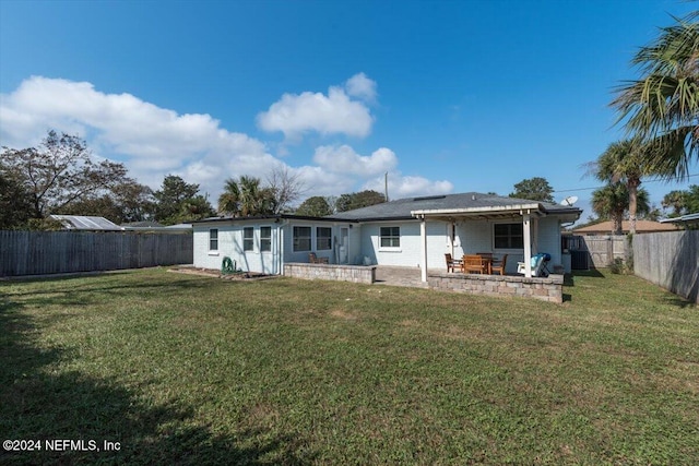 rear view of house featuring a patio area and a yard