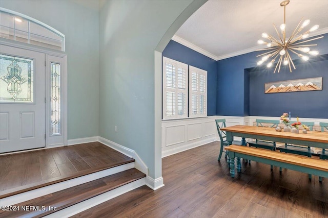 foyer with crown molding, wood-type flooring, and an inviting chandelier