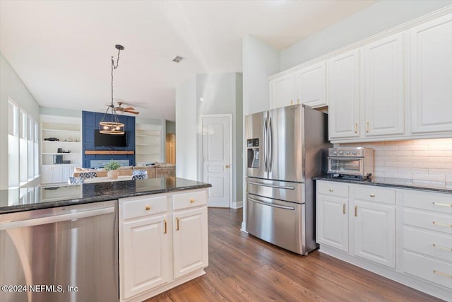 kitchen with dark hardwood / wood-style floors, hanging light fixtures, stainless steel appliances, dark stone counters, and white cabinets