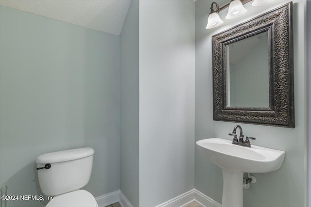 bathroom featuring toilet, a textured ceiling, and vaulted ceiling