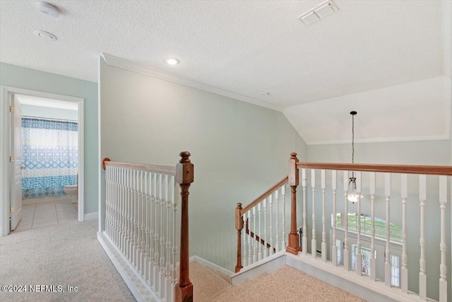 hallway with lofted ceiling, a textured ceiling, a chandelier, and light colored carpet