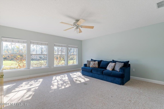 living room with light carpet, a textured ceiling, and ceiling fan