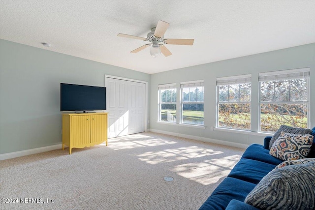 living room featuring a textured ceiling, light colored carpet, and ceiling fan