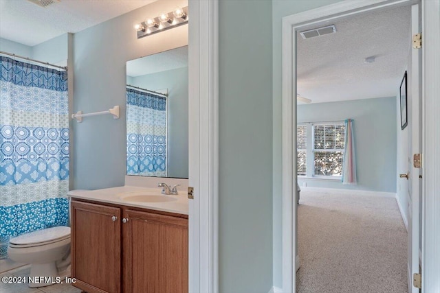 bathroom with vanity, a textured ceiling, toilet, and walk in shower