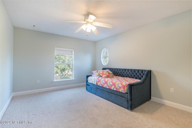 carpeted bedroom featuring ceiling fan and a textured ceiling