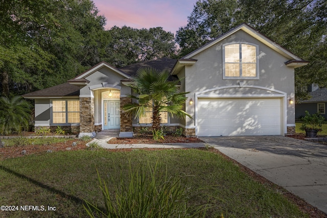 front facade featuring a garage and a yard