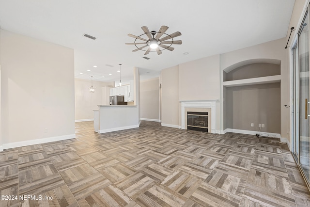 unfurnished living room with ceiling fan, built in features, and light parquet flooring