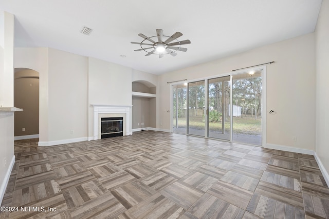 unfurnished living room featuring built in features, ceiling fan, and light parquet floors