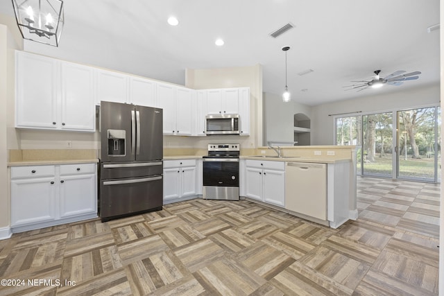 kitchen featuring stainless steel appliances, sink, kitchen peninsula, hanging light fixtures, and white cabinets