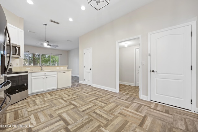 kitchen with sink, ceiling fan, white cabinetry, appliances with stainless steel finishes, and light parquet flooring