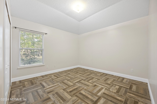 empty room featuring a textured ceiling and parquet floors