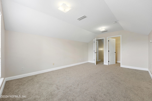 additional living space with vaulted ceiling and carpet flooring