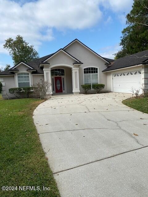 ranch-style home featuring a garage and a front lawn