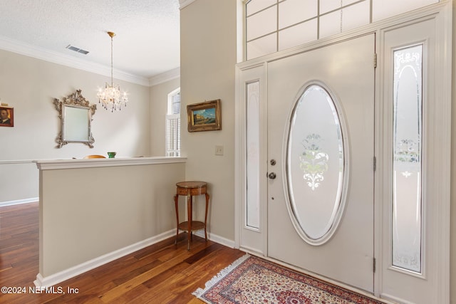 entryway featuring crown molding, a textured ceiling, an inviting chandelier, and dark hardwood / wood-style floors