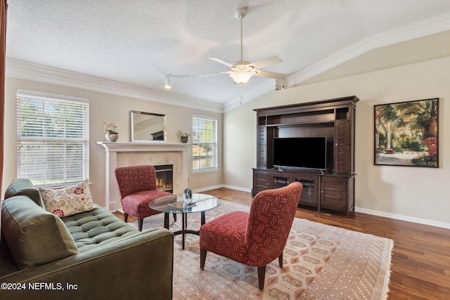 living room featuring lofted ceiling, ceiling fan, a textured ceiling, wood-type flooring, and ornamental molding