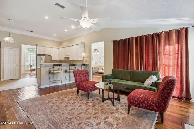 living room with lofted ceiling, crown molding, light wood-type flooring, and ceiling fan