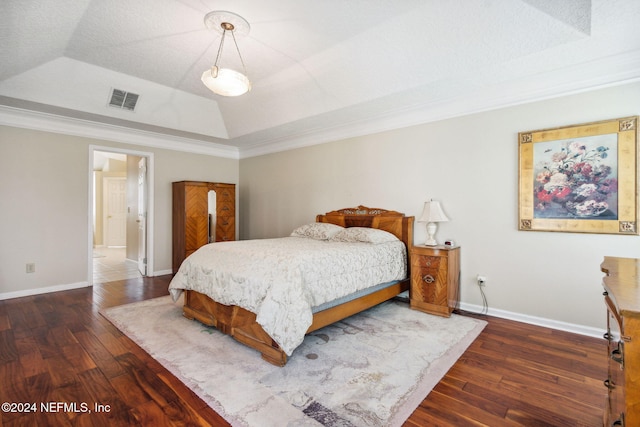 bedroom with crown molding, dark hardwood / wood-style floors, a textured ceiling, and a raised ceiling