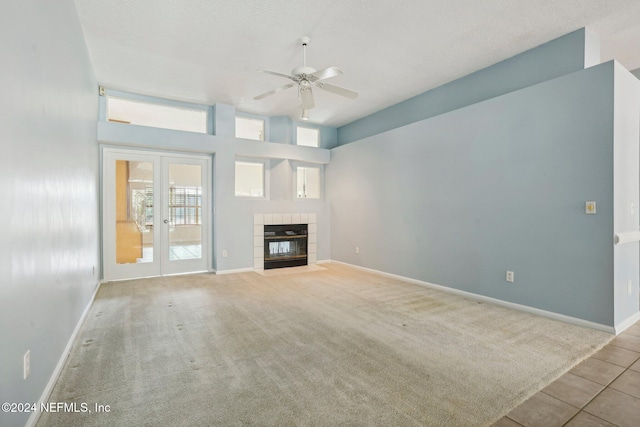 unfurnished living room featuring ceiling fan, a tile fireplace, and light colored carpet