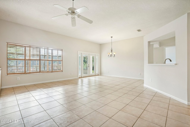 tiled spare room with french doors, a textured ceiling, and ceiling fan with notable chandelier