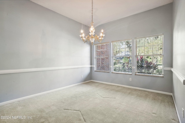 carpeted empty room with vaulted ceiling and an inviting chandelier