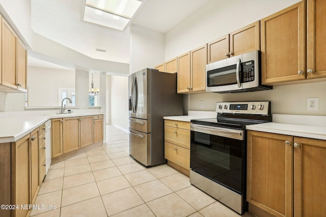 kitchen featuring kitchen peninsula, light tile patterned floors, appliances with stainless steel finishes, sink, and decorative light fixtures