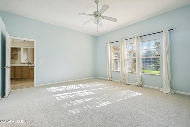 spare room featuring sink, light colored carpet, and ceiling fan