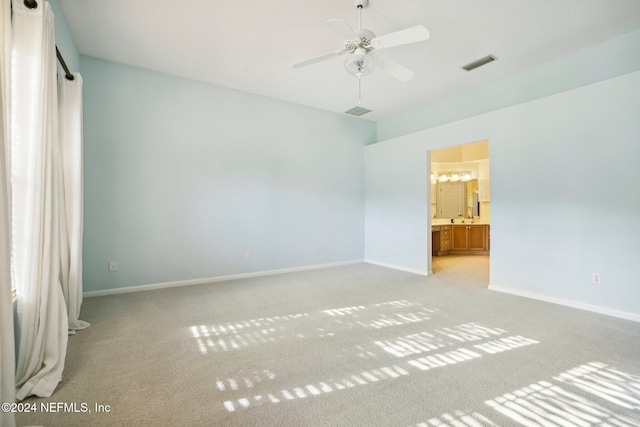 unfurnished bedroom featuring ensuite bathroom, light carpet, and ceiling fan