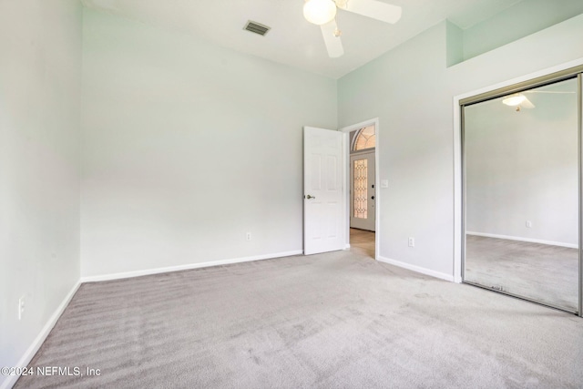 interior space with a closet, ceiling fan, carpet, and a high ceiling